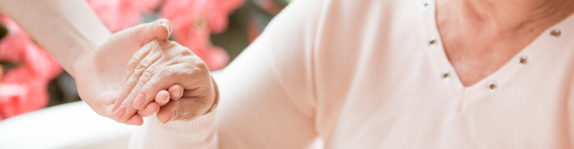 Close-up of caregiver supporting smiling senior women with walking stick