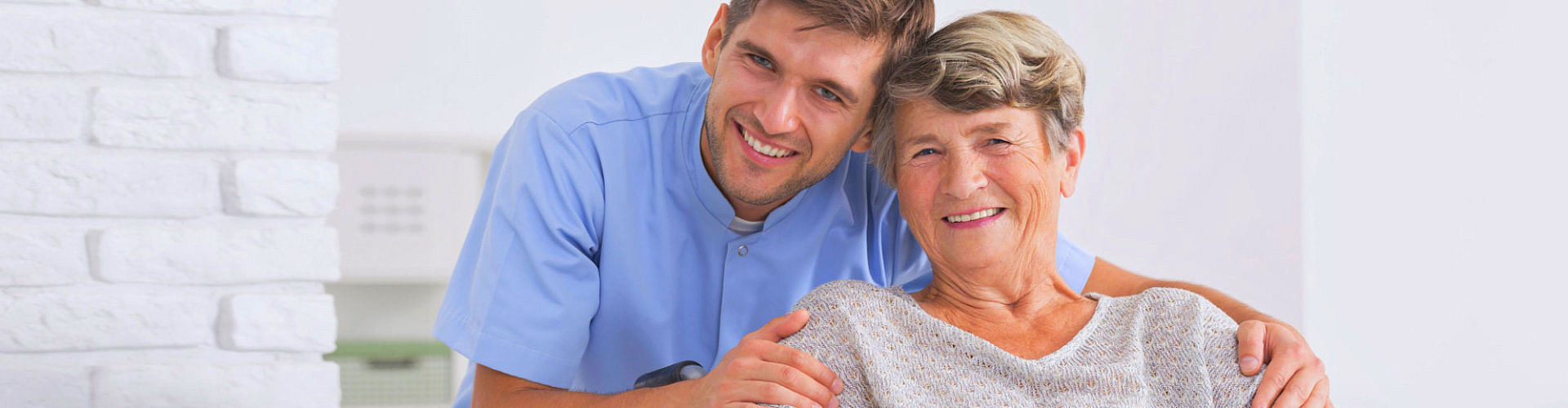 Male nurse hugging his senior women patient sitting on a wheelchair